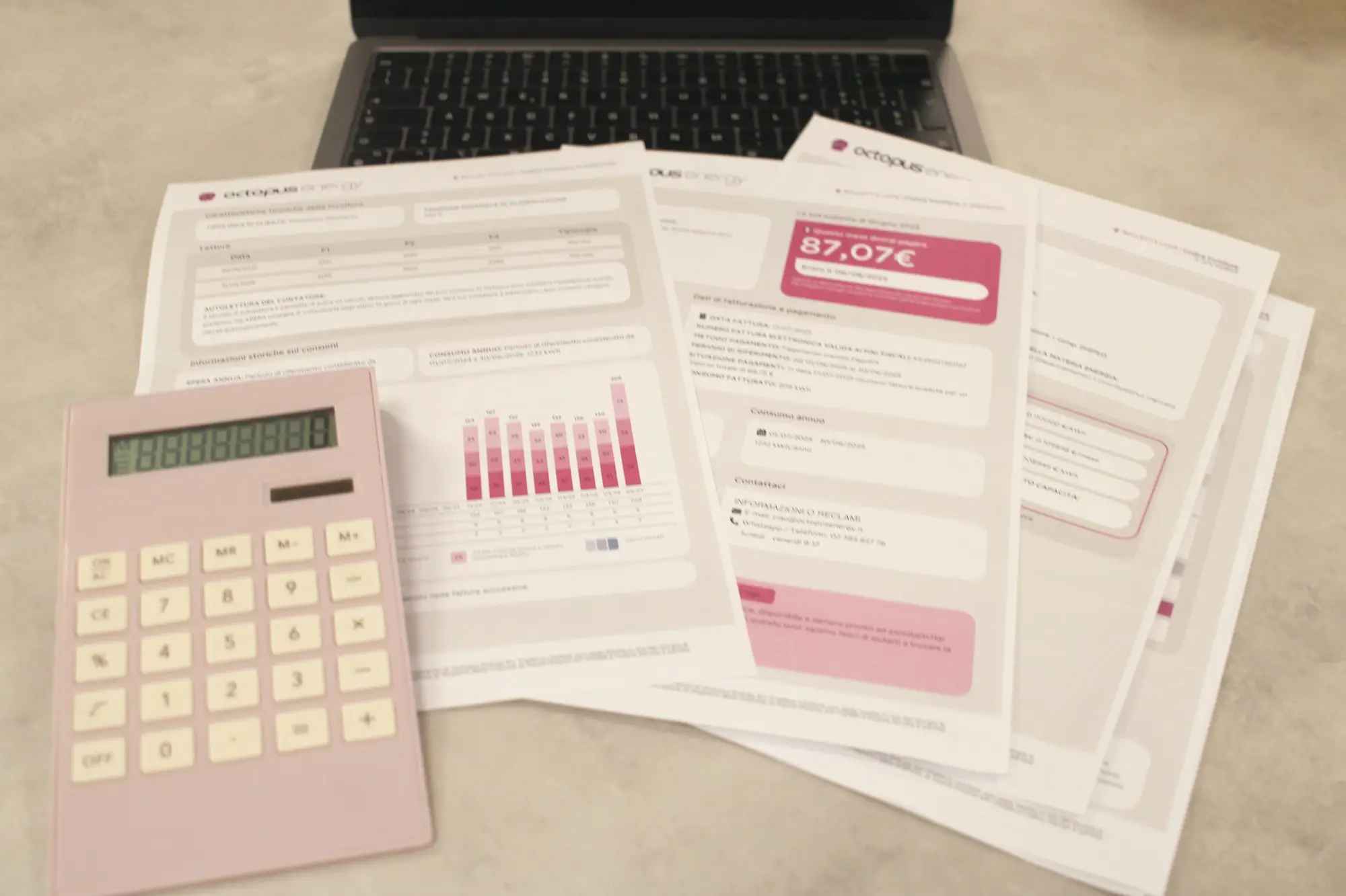 Bills, a calculator and a laptop laid out for reviewing business finances