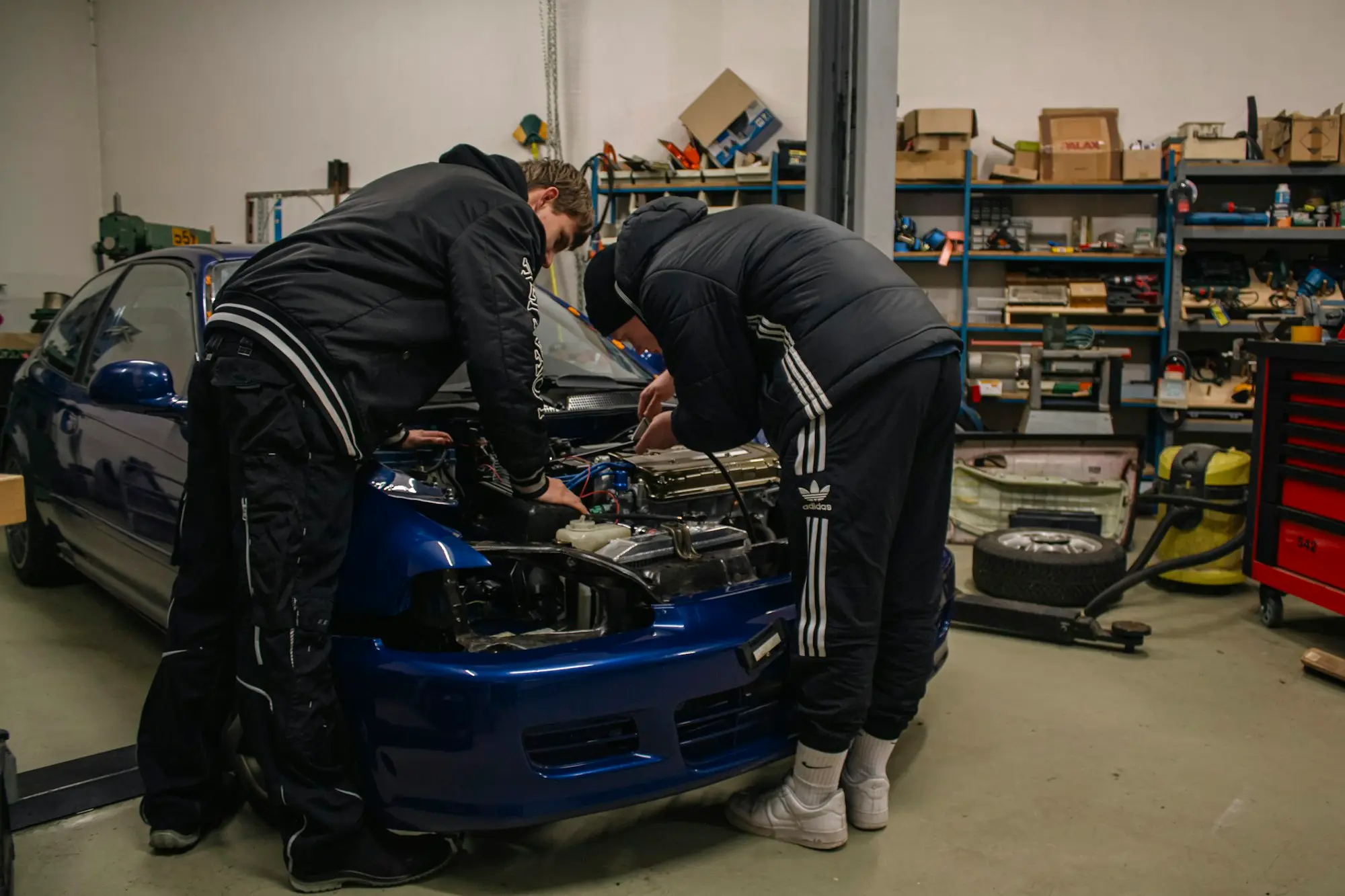 Experienced mechanic and a younger worker working on a car in a workshop