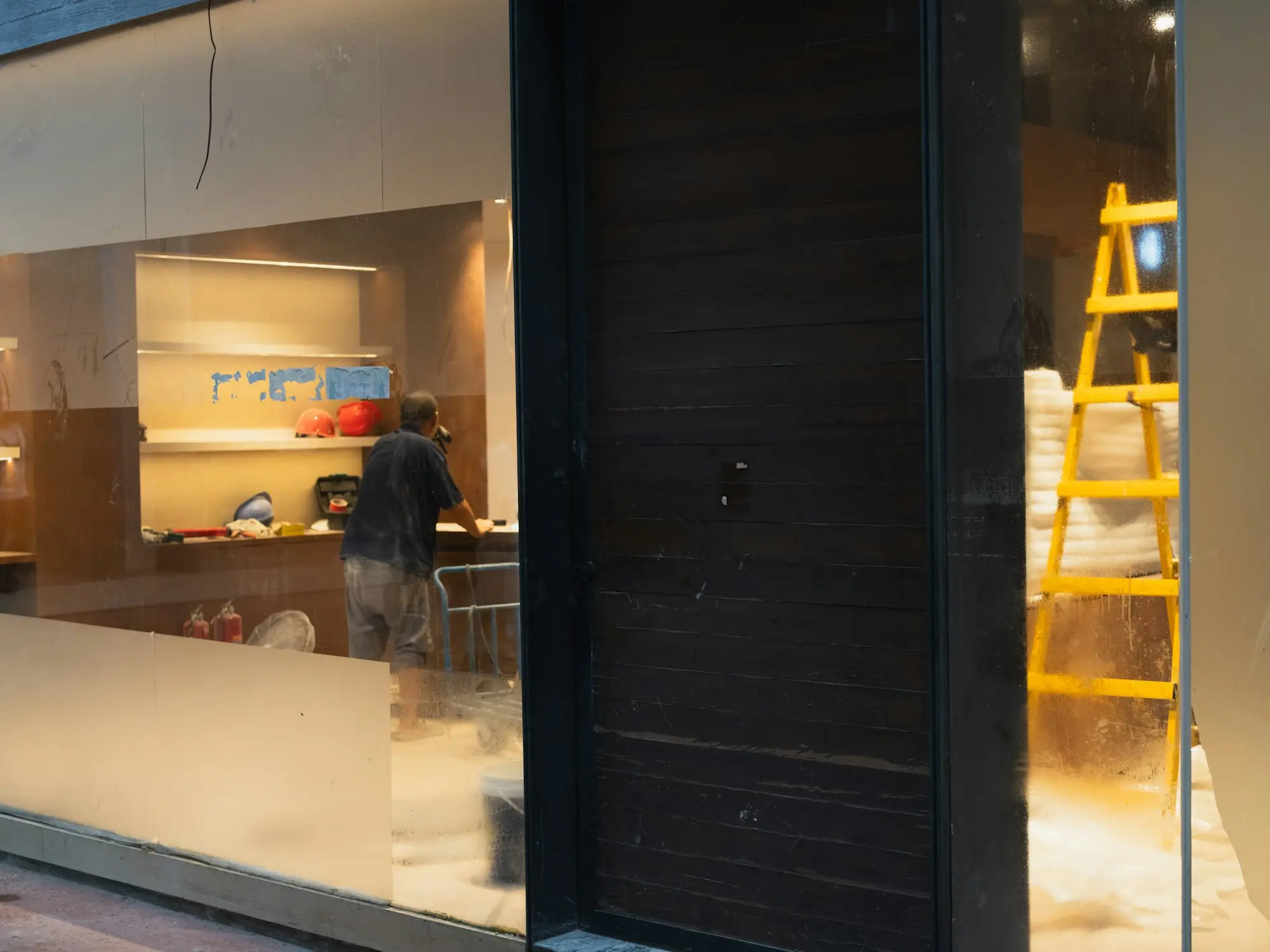 Tradesperson working inside a shop under renovation with a yellow ladder